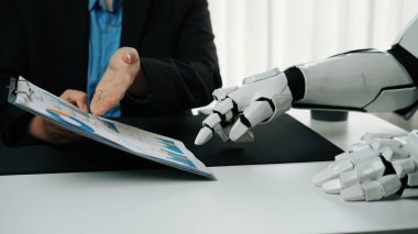 Bir insan ve robot bir iş toplantısına katılıyor, sunumlar ve belgeler aracılığıyla iletişim ve işbirliği sergiliyor. Teknoloji temaları için ideal. Haylazlık.