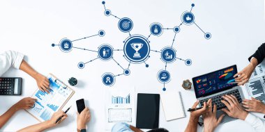 Bu görüntü, ekip üyelerinin performans ve büyüme verilerini grafik ve teknoloji kullanarak analiz ederek yenilikçi fikirler ve stratejiler geliştirdikleri işbirlikçi bir iş toplantısı kaydeder. Dostluk