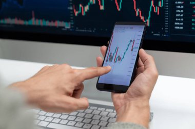 Akıllı borsa yatırımcıları ekranda akıllı telefon ile piyasa borsasını işaret ederek dizüstü bilgisayarın yanı sıra en yüksek dinamik yatırım oranını göstererek, modern işyerindeki veri planlamasına odaklanıyorlar. Bireysel.