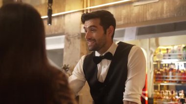 Akıllı barmenin VIP konuğuyla dostça sohbet etmesine odaklanıyorum. Cuma gecesi özel gece partisinde müşterilerin arka tarafındaki lüks tezgahta oturuyorlar. Vinosity.