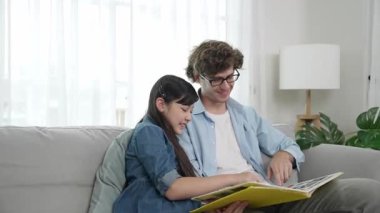 Beyaz bir baba ve tatlı bir kız kanepede otururken masal kitabı okuyorlar. Mutlu bir baba, sevimli bir Amerikan çocuğuna, birlikte zaman geçirirken hayal gücünün gelişmesi için hikaye anlatıyor. Pedagoji.