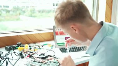 Beyaz öğrenci bilgisayar ekranına bakarken mühendislik komut ya da programlama sistemine bakıyor. Bilgisayarla ve elektronik aletlerle çalışan gençlerin arka plan görüntüsü...