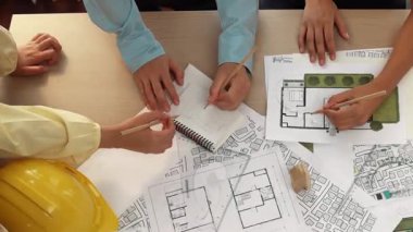 Mimari belge, ölçüm aracı ve ahşap blokların modern ofiste etrafa saçıldığı bir masa üzerinde yapı inşaatı ile ilgili mimar ve güvenlik mühendisi tartışması. Tanımlama.