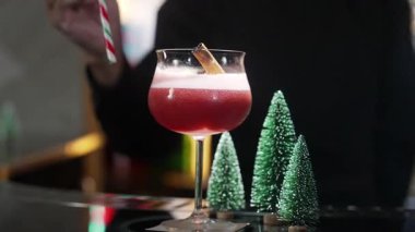 Kapanış barmeninin servis ettiği kokteyl kokteyli temalı karışık Noel temalı şeker kamışı ve noel ağacı şenlik içeceğinin yeşil neon karıyla süslenmiş tarçınlı lüks bar. Vinosity.