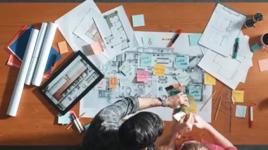 Planlar ve notlarla toplantı masasında dururken mühendisin inşaat tasarımı için birlikte çalışması zaman aşımı. Paletlerden renk seçen iç mimarın üst görünümü. Sempozyum.