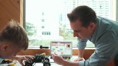 Öğretmen yardımı öğrencisi araba modelini tamir ediyor ve liseli çocuk STEM sınıfında robotu tamir etmek için ekipmanları dinlerken programlama sistemi ya da kodlama komutu veriyor. Arkadan bak. Öğretim