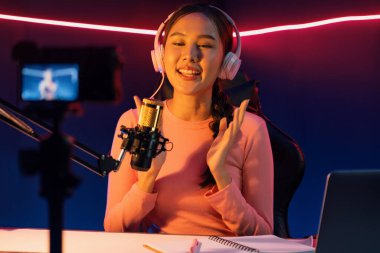 Yaratıcı yayın kanalı sosyal medyada pozitif podcasttaki dinleyicilerle birlikte müziği dinliyor, pastel renkli kulaklıklar takıyor, neon stüdyodaki kameraların mikrofon kayıtlarını kullanıyor. Taktik.