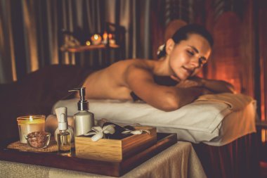 Aromaterapi masajı ambiyansı ya da spa salonu kompozisyon düzeneği bulanık kadınlara odaklı dekor mumları ve spa aksesuarları ile tatil köyü veya otel arka planında keyifli aroma spa masajı yapan. Sessiz.