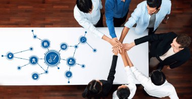 Bir masa üzerinde işbirliği yapan çeşitli profesyoneller grubunun havadan görüşü, bağlantıları ve fikirleri gösteren dijital grafikler, takım çalışmasını ve yeniliği sembolize ediyor. Dostluk