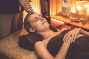 Beyaz kadın stres önleyici kafa masajı yapmaktan ve lüks otel veya otelde sıcak mum ışığında yüz güzelliği eğlencesi yapmaktan zevk alıyor. Sessiz.