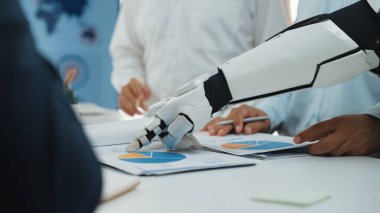 Robot bir kol, bir şirket toplantısında ayrıntılı finansal çizelgeleri ve grafikleri analiz eder. Modern ofis ortamında yenilik, teknoloji ve işbirliğini teşvik etmek. Noogenesis