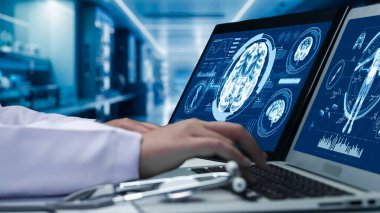 Ekranda insan anatomisi görüntüsü olan tablet ve dizüstü bilgisayar üzerinde çalışan doktorları kapatın. Beyin ameliyatına hazırlanırken el ve beyin hasarlarını kontrol eden zeki bir tıp çalışanı. İyileştirici.