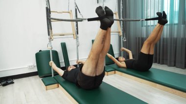Bir grup müşteri, çekirdek dayanıklılığını ve bacak bağını geliştirmek için Cadillac reformatör makinesinde pilates egzersizleri yapıyor. Sağlıklı müşterilerin daha düşük poz verip kaldırma pozlarının üst görüntüsü. Sağlıklılık. Alışkanlık.
