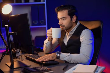 Gülümseyen zeki işadamı, elinde kahve fincanı olan satış ekibiyle buluşuyor ve geceleri Mor Neon Light Home Office 'deki bilgisayar ekranında ürün hedef pazarını araştırıyor. Tahmin et..