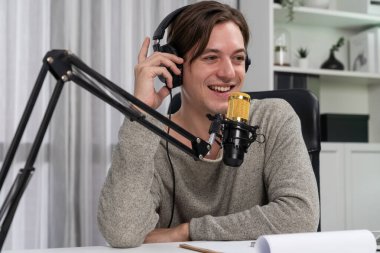 Sunucu kanalı, gülümseyen akıllı yayıncı kaydı, senaryosu ve akıllı telefonuyla sosyal medyada sohbet programı, kulaklık takarak modern ev stüdyosundaki video flamalarını kaydediyor. Bireysel.