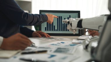 Bir iş ekibi, dijital ekranda sunulan verileri analiz ederek bir ofis ortamında insanlar ve robotik teknoloji arasındaki işbirliğini ön plana çıkarıyor. Noogenesis