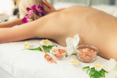 Lüks spa salonlarında sıcak mum ışığında cilt bakımı yaptıran kadın müşteri. Sağlık Spa vücut fırçasında tuz temizleme güzellik tedavisi. Sessiz.