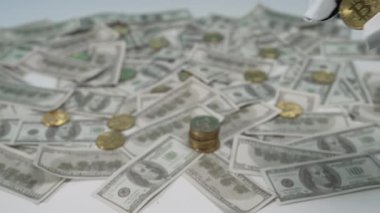 Robot bir el, teknoloji ve finans kavşağını modern para ve yatırımla tasvir eden Amerikan dolarlarından oluşan bir yatağın üzerinde bir Bitcoin parayı dikkatle tutuyor. MZL