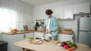 Mutlu baba yemek pişirirken müziğe geçiyor ve modern mutfakta öğle yemeği hazırlıyor. Aktif baba, sebze ve mutfak gereçleri ile çevrili sağlıklı yemek ya da salata yaparken şarkıyla dans ediyor. Pedagoji.