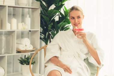 Güzellik ya da vücut bakımı güzellik salonu yaşam tarzı konsepti. Bornoz giyen bir kadın lüks otel kaplıcalarında ya da tatil odasında içkiyle rahatlıyor. Tatil ve boş zaman rahatlığı. Sessiz.