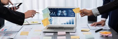 Analizci ekibi yaratıcı ve analitik beyin fırtınası fikri için bilgisayar ekranında BI veri paneli olan yapışkan bir not kullanıyor. Pazarlama stratejisi için finansal veri görselleştirme teknolojisini analiz et. Dahi.