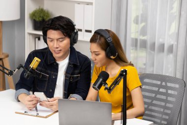 Gülümseyen radyo etkili sunucular, kulaklık takıp sosyal medyayı canlı yayında dinleyicilere telefon ve dizüstü bilgisayarla canlı yayınlıyorlar. İnfobahn.