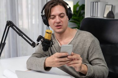 Akıllı yayıncının sunucu kanalı canlı sosyal medya yayını ile akıllı telefon kullanarak dinleyiciyle sohbet ediyor, kulaklık takarak modern ev stüdyosunda video kaydediyor. Bireysel.