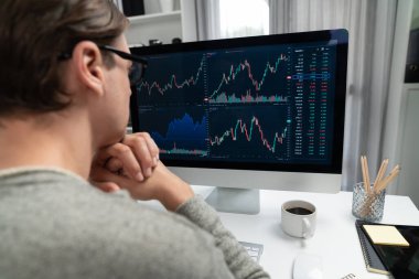 Bilgisayar ve dizüstü bilgisayarı kullanarak, çalışma masasındaki dinamik artırılmış borsa grafiğinin en yüksek kar değerini araştıran bir tüccar, modern ofisteki ekrandaki döviz kuru değerini analiz ediyor. Bireysel.