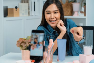 Genç, güzel Asyalı kozmetik makyaj ruju matte pastel rengini modern odadaki sosyal medyada kol testi tanıtımında en çok satanlar listesinde gösteriyor. Taktik.