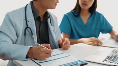 Hastane masasında birlikte çalışan ve tıbbi tedavi planlayan çeşitli profesyonel sağlık görevlileri. Takım çalışması başarılı hastalıklara ve hastalıklara yol açar. Ağır çekim. Katı.