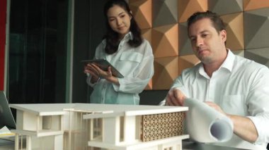 Profesyonel mimar mühendis takım tasarımı ve proje planı kullanarak ev hakkında tartışmalar. Proje yöneticisi, ev inşaatını mimari modeli masaya yerleştirilmiş mühendislere açıklıyor. Yönlendirici.