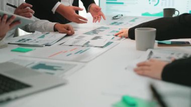 Çeşitli bir iş ekibi bir masanın etrafında toplanarak veri ve grafikleri analiz etti, modern ofis ortamında stratejileri tartıştı, işbirliği ve yeniliği teşvik etti. SACTR