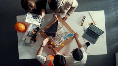 Akıllı mimar mühendis ekibinin yukarıdan görünüşü ev modelini incelerken müdürün elinde bina inşaatı hakkında sorular var. Çeşitli mühendislerden oluşan bir grup birlikte çalışıyor. Hizalama.