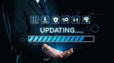 Resmi takım elbiseli profesyonel bir işadamı, modern bir iş ortamında dijital güncelleme çubuğu, teknoloji ve veri yönetimi kavramları sunuyor. Dörtgen