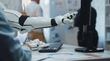 Bir robotik kol, modern işyerlerinde gelişmiş teknolojinin entegrasyonunu, verimliliği ve işbirliğini sembolize eden bir bilgisayar ekranına doğru uzanır.