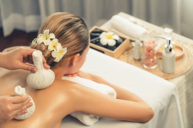 Sıcak bitkisel top spa masaj vücut tedavisi, masör kadın vücuduna nazikçe şifalı bitki torbası bastırıyor. Aromaterapi dinlenme sükuneti ve sükuneti kaplıca salonundaki atmosferi aydınlatıyor. Sessiz.