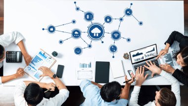 Meşgul bir ekip, iş performansını ve yeniliğini artırmak için verileri analiz ederek ve bulut teknolojisi stratejilerini tartışarak modern bir çalışma alanında iş birliği yapıyor. Dostluk