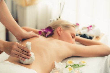 Sıcak bitkisel top spa masaj vücut tedavisi, masör kadın vücuduna nazikçe şifalı bitki torbası bastırıyor. Aromaterapi dinlenme sükuneti ve sükuneti kaplıca salonundaki atmosferi aydınlatıyor. Sessiz.