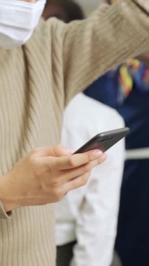 Trende cep telefonu kullanan gezgin yüz maskesi takıyor. Coronavirus hastalığı veya COVID 19 salgın ve şehir yaşam tarzı sorunu iş çıkış saati kavramında .