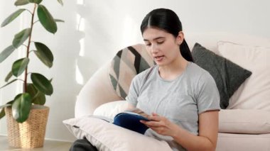 Kanepede oturan bir kadın ders kitabı okuyarak sosyal ve mesleki teknoloji bilgisini artırır ya da akıllı bir anne olmak için çocuk yetiştirir. Hayat boyu öğrenme konsepti. Uyumsuzluk.