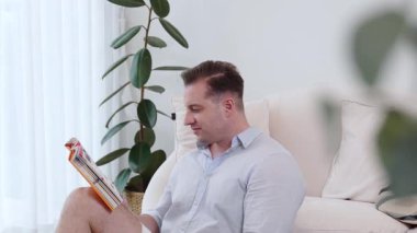 Kanepede oturan orta yaşlı bir adam, sosyal ve teknolojik mesleki gelişmeler hakkında ders kitabı okur ya da çocukları iyi bir yetişkin baba olmak için yetiştirir. Hayat boyu öğrenme konsepti. Uyumsuzluk.