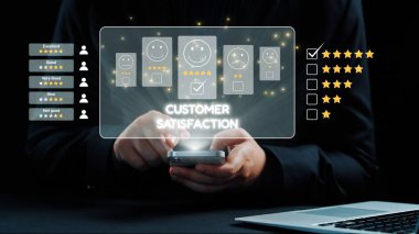 Akıllı telefon arayüzü üzerinden müşteri memnuniyeti geri bildirimi sağlayan, duygu simgeleri ve derecelendirme yıldızlarıyla iş dünyasındaki dijital eleştirilerin önemini vurgulayan bir kişi. Dörtgen