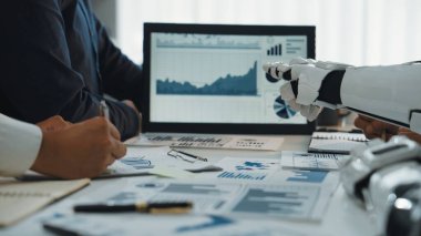 Bir iş ortamında insan ve robot takım çalışmasını gösteren dinamik bir sahne. Gelişmiş üretkenlik için analitik grafikler, veri görselleri ve modern teknoloji entegrasyonu. Noogenesis