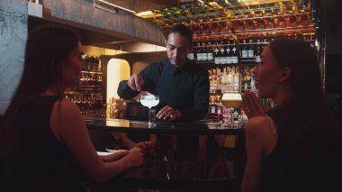 Asyalı akıllı barmen votka bardağını karıştırdı. Çiçek, lüks tezgah barında özel içki yapan güzel müşteriye servis edildi. Ferahlatıcı alkol gece hayatı lüksü. Vinosity.