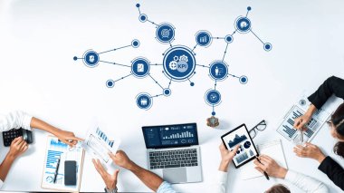 Bu resim, anahtar performans göstergelerine odaklanmış işbirlikçi bir iş stratejisi toplantısını betimliyor. Katılımcılar veri analizi ve içgörü için modern araçlar kullanıyorlar. Dostluk