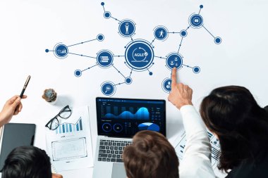 Diz üstü bilgisayarda veri analizi kullanarak, takım çalışması ve yenilikçi fikirleri dinamik ofis ortamında sergileyerek çevik iş stratejileri üzerinde işbirliği yapan bir grup profesyonel. Dostluk