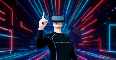 VR gözlüklü profesyonel erkek oyuncu parlayan neon ışıkla oyun oynuyor. Heyecanlı oyuncu artırılmış gerçeklik teknolojisi yeniliklerini kullanarak metaevrene bağlanmayı seviyor. Yaratıcılık.