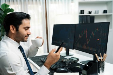 Elinde telefon dinamiğine odaklanan kahve fincanı tutan borsa yatırım ekranı veri analizini karşılaştırarak iç işlerinde yüksek kârlı finans teknolojisi pazarına yatırım yapıyor. Tahmin et..