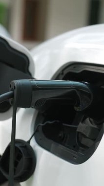 İlerici ebeveynler kızlarını okuldan alırken elektrikli araba ve yenilenebilir enerji kavramını kullandılar, evdeki EV otomobil için şarj istasyonu. Alternatif eko taşımacılığı.