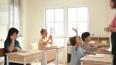 Çeşitli zeki öğrenciler sınıfta çalışırken ve mutlu öğretmenleri dinlerken soruları cevaplamak için ellerini kaldırdılar. Çok kültürlü çocuklar gönüllü oldular, oy verdiler, soru sordular. Pedagoji.